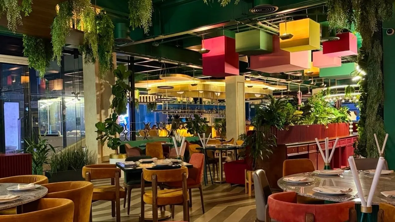 El salón de Hungerss: plafón verde, plantas colgantes y sillería en terracota y mostaza.