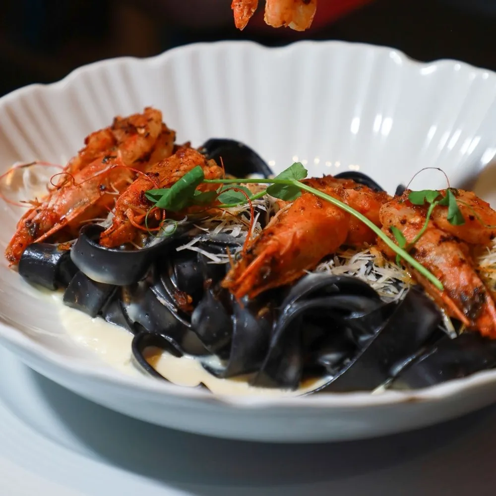 Fettuccine de tinta de calamar coronado con camarones.