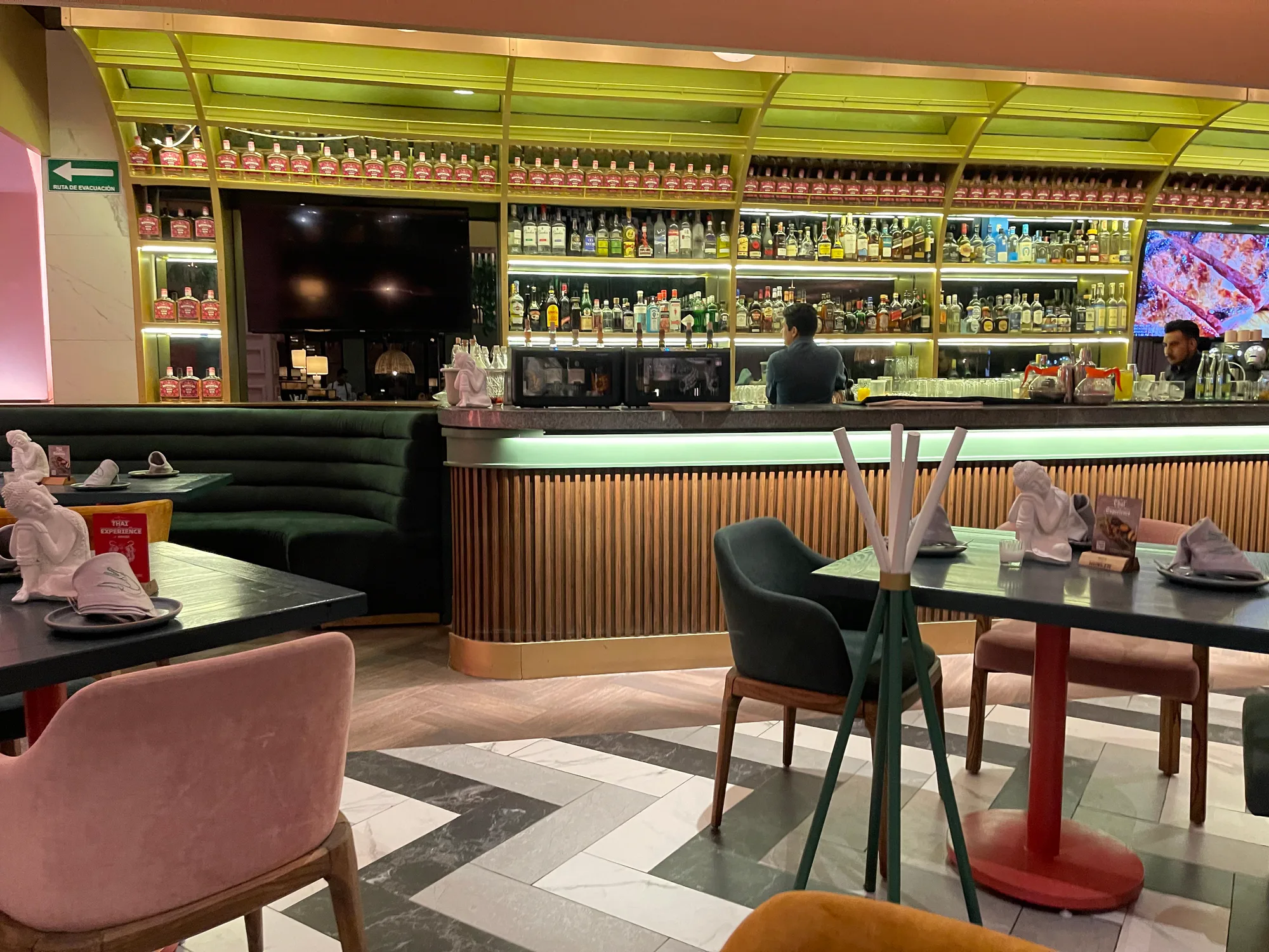 La barra: el anaquel verde de botellas, las banquetas y el suelo de espiga.
