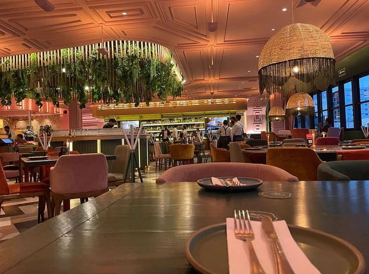 Una mesa puesta en primer plano, con el comedor detrás.